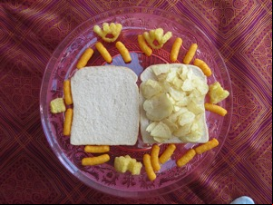 Overhead view of potato crisps on white bread with snacks