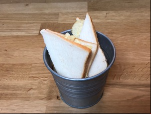 Crisps in sliced white bread in a metal bucket