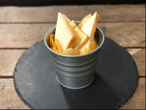 Metal bucket containing crisps and sandwich