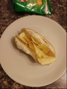 Finger roll filled with potato crisps, crisp bag visible