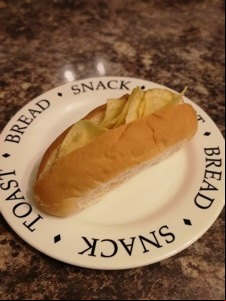 Split finger roll filled with potato crisps on a plate