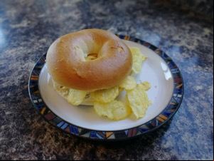 Bagel overfilled with potato crisps on a plate