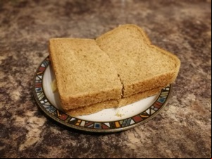 Halved brown crisp sandwich on a plate on granite