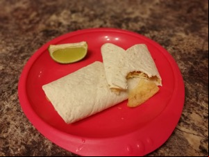 Crisp-filled wrap with a bite taken out alongside lime