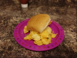 White roll overflowing with crisps on a pink plastic plate