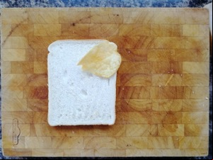 One crisp on white bread on a chopping board