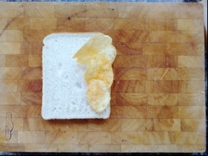 Three crisps on white bread on a chopping board