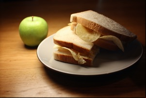 White crisp sandwich cut in half alongside an apple